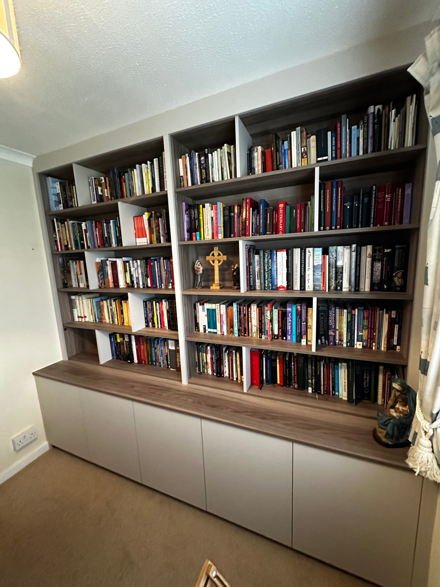 Full-height fitted bookcase with walnut shelving and concealed base cupboards