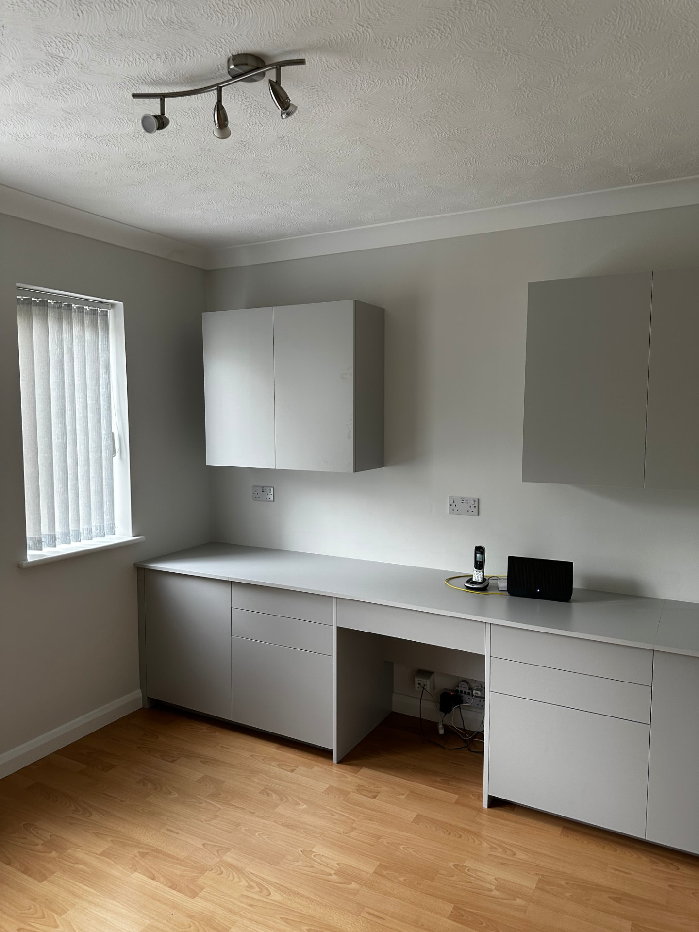 Minimal white fitted home office desk with drawers and wall-mounted cupboards
